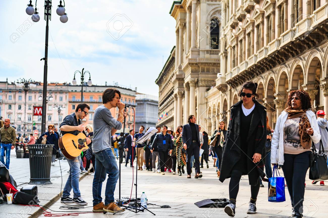 MILAN, ITALY - 14 APRIL 2018 - Unidentified street performers play guitar and sing the song in public area around Duomo di Milano among tourists